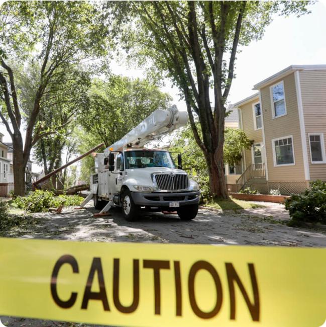A large utility truck with a crane attachment is parked on a residential street.